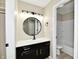 Well-lit bathroom with a black vanity, a marble countertop, and a round mirror at 6352 Watercrest Way, Indianapolis, IN 46278