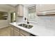Bright kitchen featuring a stainless steel sink, modern faucet, stone countertop, and mosaic tile backsplash at 6352 Watercrest Way, Indianapolis, IN 46278