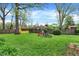 Large backyard featuring a playground, storage shed, mature trees and grass, ideal for Gathering entertainment at 6837 Doris Dr, Indianapolis, IN 46214