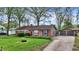 Charming brick ranch home featuring a well-manicured lawn, flower beds, a concrete driveway, and an attached garage at 6837 Doris Dr, Indianapolis, IN 46214