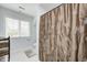 Well-lit bathroom with a window, a shower with floral curtain, white tile, and a gray bath mat at 7653 Carriage House Way, Zionsville, IN 46077