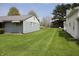 Backyard with a lush lawn, an outbuilding with light blue siding, and mature trees in the background at 8341 N Washington St, Sheridan, IN 46069