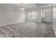 Bright living room with gray wood-look floors, white walls, and a large window with natural light at 901 Palomino Pl, Bargersville, IN 46106