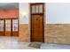 Hallway with brick details and wood door leading to unit M7 and view of glass lobby doors at 920 E 62Nd St # Apt M7, Indianapolis, IN 46220