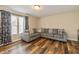 Comfortable living room area with a gray sectional, wood-look flooring, and bright natural light from the nearby window at 9307 W Dockside Cir, Pendleton, IN 46064