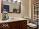 Bathroom with wood cabinets, large mirror, and shower with patterned curtain at 1018 Redwood Dr, Lebanon, IN 46052