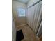 Bathroom with a white shower curtain covering the tub, tile floor, and window at 1050 Jefferson Ave, Indianapolis, IN 46201