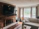 Cozy living room showcasing a brick fireplace with a wooden mantel, natural lighting, and comfy furniture, ideal for relaxing evenings at 106 Walnut St, Southport, IN 46227