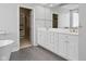 Bathroom featuring double sinks with white cabinets, a large mirror, and walk-in closet with custom shelving at 11484 Lake Stonebridge Ln, Fishers, IN 46037
