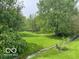 Expansive backyard with lush green grass, mature trees, and a small creek at 11748 E 10Th St, Indianapolis, IN 46229