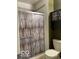 Bathroom featuring a shower with a decorative shower door and commode at 11748 E 10Th St, Indianapolis, IN 46229