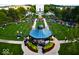 Aerial view of a park with crowds, bandstand, lush green lawns, and mature trees at 12873 Tradd St # 2B, Carmel, IN 46032
