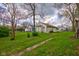 The backyard features a grass yard leading to a white sided house, with trees and bushes at 1467 W 33Rd St, Indianapolis, IN 46208
