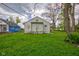 The backyard features a lush lawn, a house with white siding, and green trees and vegetation at 1467 W 33Rd St, Indianapolis, IN 46208
