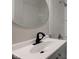 Close up of renovated bathroom with gray vanity, black faucet, and a large, round mirror at 1467 W 33Rd St, Indianapolis, IN 46208