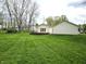 Spacious backyard features a well-maintained lawn, mature trees, and a back deck attached to a light yellow vinyl house at 1506 Field Dr, Noblesville, IN 46060