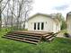 Backyard view with wooden deck and stairs to large lawn, surrounded by mature trees and siding of the house at 1506 Field Dr, Noblesville, IN 46060