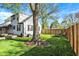 Large backyard featuring mature trees, fire pit, wooden fence, and lush green lawn at 2221 Douglas Rd, Indianapolis, IN 46220