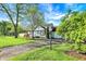 Charming blue home featuring a well-kept lawn, mature trees, and a paved driveway at 2221 Douglas Rd, Indianapolis, IN 46220