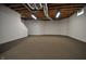 Unfinished basement with painted brick, neutral carpet, and exposed ductwork offers a blank slate for future living space at 2363 N Pennsylvania St, Indianapolis, IN 46205