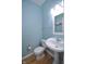 Powder room featuring blue accent walls, hardwood floors, and pedestal sink at 2363 N Pennsylvania St, Indianapolis, IN 46205