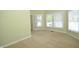 Spacious living room featuring three bright windows with white blinds, neutral carpet and light green walls at 2363 N Pennsylvania St, Indianapolis, IN 46205