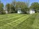 Spacious backyard with lush, manicured lawn, mature trees, and detached white garage or shed at 2842 Sangster Ave, Indianapolis, IN 46218