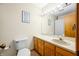 Traditional bathroom with a wood vanity, white sink, mirror, and a toilet adjacent to a decorative framed sign at 3165 Sycamore Dr, Columbus, IN 47203
