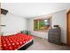 Cozy bedroom with neutral carpet, gray walls, a red quilt bed, a window, and a dark wood dresser at 3165 Sycamore Dr, Columbus, IN 47203