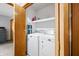 Stacked laundry room with washer and dryer, laundry supplies, and ironing board behind bifold wood door at 3165 Sycamore Dr, Columbus, IN 47203
