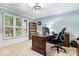 Well-appointed home office with a wooden desk, built-in shelving, and a large window overlooking the outdoors at 3444 Briar Pl, Carmel, IN 46033