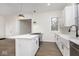 Open kitchen area with island cooktop, white cabinetry, quartz countertops, undermount sink, and wood-look vinyl flooring at 3845 Cornelius Ave, Indianapolis, IN 46208