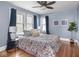 Cozy bedroom with a ceiling fan, hardwood floors, and a large window with natural light at 5181 E Pleasant Run Pkwy S Dr, Indianapolis, IN 46219