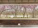 Covered front porch with brick railing offering scenic views of blooming trees at 5181 E Pleasant Run Pkwy S Dr, Indianapolis, IN 46219