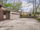 Spacious detached garage with a wide driveway, surrounded by a lush backyard and mature trees, ideal for storage at 5181 E Pleasant Run Pkwy S Dr, Indianapolis, IN 46219