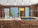 Granite kitchen island with a sink, cooktop, and wooden cabinets at 5181 E Pleasant Run Pkwy S Dr, Indianapolis, IN 46219