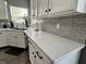 This kitchen counter boasts white cabinets, sleek hardware, a gray backsplash, and stylish countertops at 6360 E Chapel Hill Ct, Camby, IN 46113