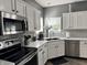 This lovely kitchen features stainless steel appliances, white cabinets, and gray subway tile backsplash at 6360 E Chapel Hill Ct, Camby, IN 46113