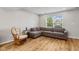 Open living room with wood floors, large gray sofa, rocking chair, and a view through the bright window at 7163 Cordova Dr, Indianapolis, IN 46221