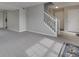 Open-concept living room featuring modern gray carpeting, light gray walls, and a staircase leading upstairs at 7202 Red Lake Ct, Indianapolis, IN 46217