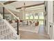 Open living room with modern staircase, large windows offering backyard views, and cozy seating by a fireplace at 728 Christin Ct, Plainfield, IN 46168