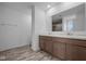 Bathroom featuring double sinks, wood cabinets, a large mirror, and elegant wood-look flooring at 7417 Waylon Way, Indianapolis, IN 46239