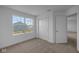 Sunlit bedroom with neutral carpet, a large window overlooking a home, and a double closet at 7417 Waylon Way, Indianapolis, IN 46239