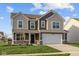 Two-story home featuring a white garage door, brown siding and coordinated stonework on the facade at 7417 Waylon Way, Indianapolis, IN 46239