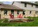 An exterior view of a stone and siding house with a backyard deck furnished with red chairs at 7423 Scarborough Blvd E Dr, Indianapolis, IN 46256