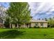 Attractive two-story home with stone accents, green shutters, a well-maintained lawn, and mature trees at 7423 Scarborough Blvd E Dr, Indianapolis, IN 46256