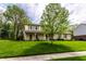 Attractive two-story home with stone accents, green shutters, a well-maintained lawn, and mature trees at 7423 Scarborough Blvd E Dr, Indianapolis, IN 46256