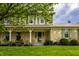 Inviting front porch of home with stone accents, green shutters, well-manicured lawn and landscaping at 7423 Scarborough Blvd E Dr, Indianapolis, IN 46256