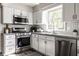 Modern kitchen with stainless steel appliances, white cabinets, and gray countertops with stylish backsplash at 7423 Scarborough Blvd E Dr, Indianapolis, IN 46256
