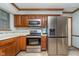 Well-lit kitchen featuring stainless steel appliances, oak cabinets, and tile backsplash with modern lighting at 7856 Trotwood Cir, Indianapolis, IN 46256